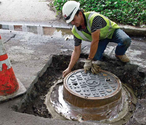 Man installing manhole in street